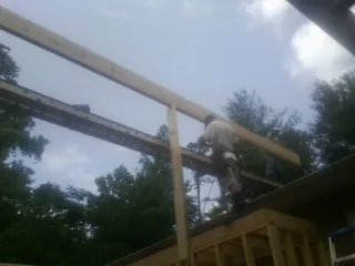 Carpenter setting a ridge beam over a new addition frame — Ice Dam Removal by Roofing Brothers in Irving