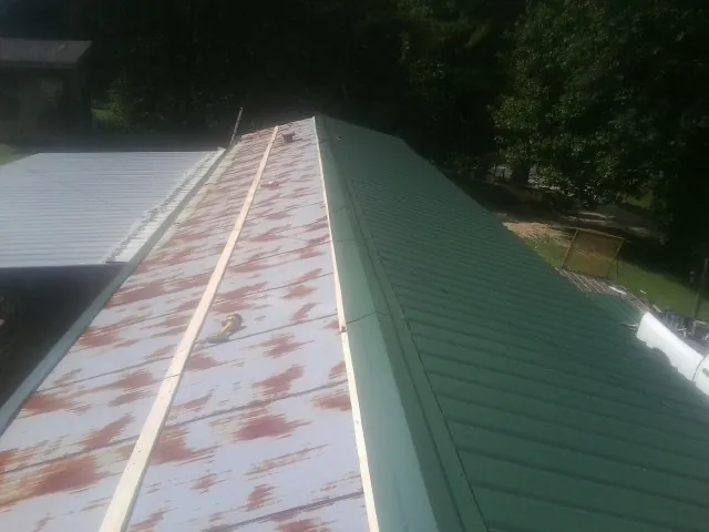 Old rusted panels beside newly installed green metal roofing — Wind Damage Roof Repair by Roofing Brothers in Irving