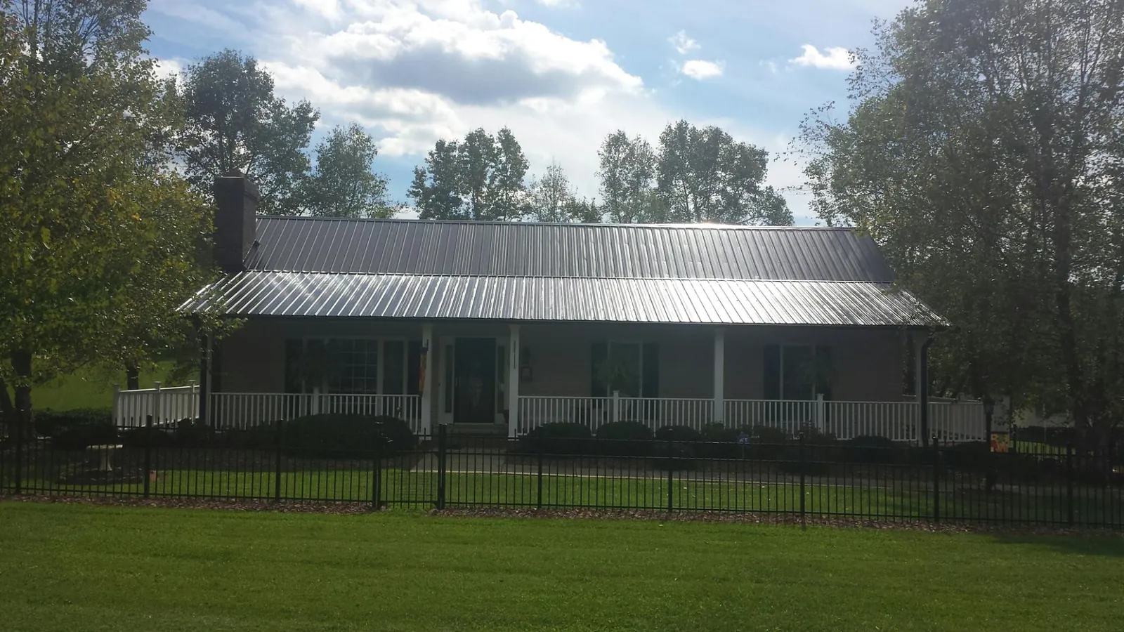 Gray metal roof on a brick ranch with a full width front porch — Gutter Guard Installation work by our crew in Irving
