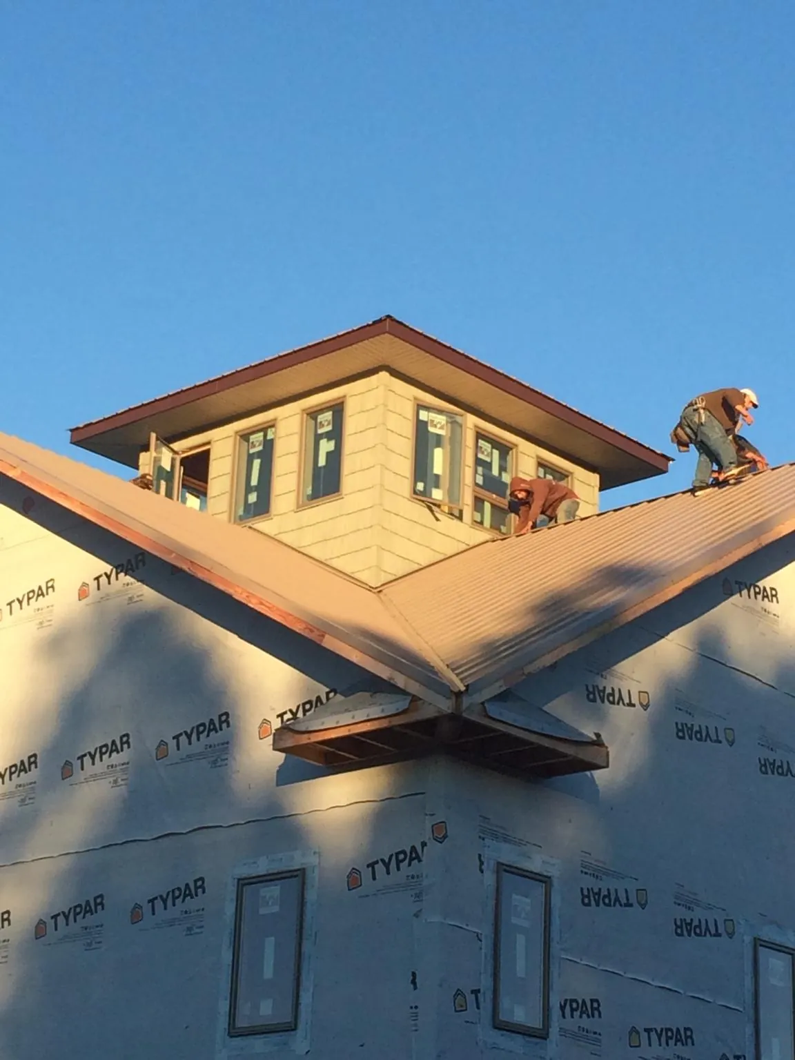 Roofers working around a rooftop cupola on a new metal roof at sunset — Roof Waterproofing in Irving by Roofing Brothers
